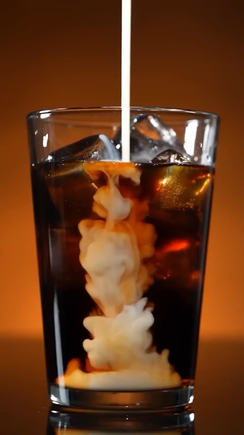 Milk swirling into a glass of Fountain Brew cold brew over ice